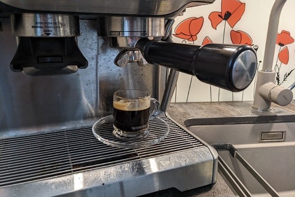 Espressotasse mit Espresso unter Kaffeemaschine