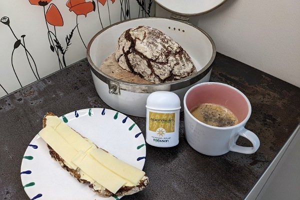 Brotdose mit Brot, Teller mit Käsebrot, Tasse Kaffee, Dose Spermidin